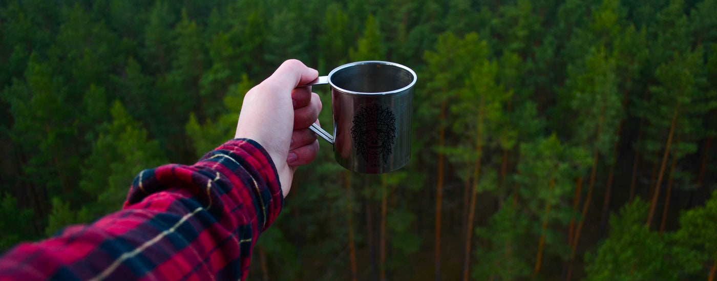 A person wearing a plaid flannel shirt holding a cup of coffee.
