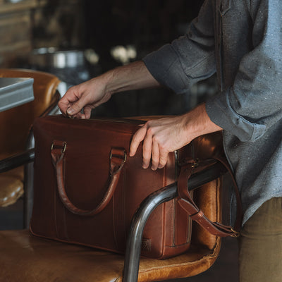Artisan-crafted leather briefcase in warm tan, equipped with sturdy handles and detachable shoulder strap.