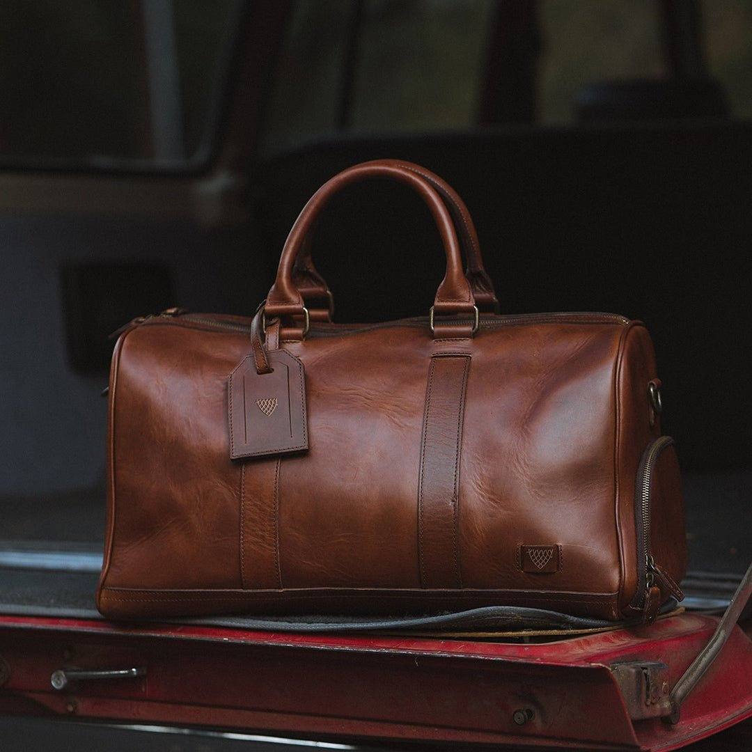 High-quality leather duffle with robust carry handles, adjustable shoulder strap, and large zippered opening.