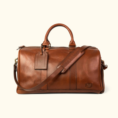 High-quality leather duffle with robust carry handles, adjustable shoulder strap, and large zippered opening.