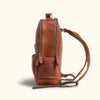 Side View - Rugged brown leather backpack viewed from the side, featuring zipper compartments and adjustable shoulder straps for comfortable carrying.