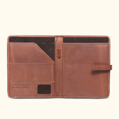 Open dark oak leather padfolio displaying compartments for tech devices, writing tools, and documents, with a classic strap closure.
