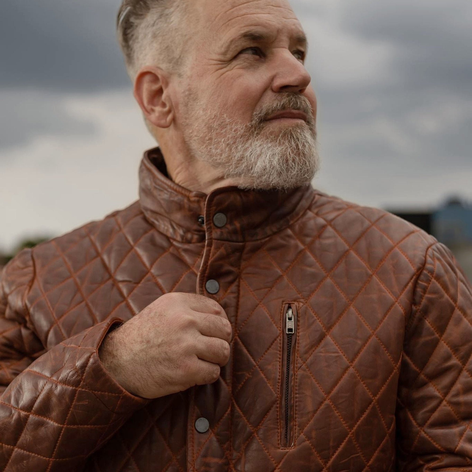 Man adjusting the collar of the Highlands Quilted Leather Jacket in Whiskey Brown.