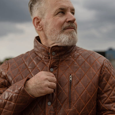 Man adjusting the collar of the Highlands Quilted Leather Jacket in Whiskey Brown.