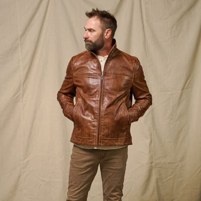 Man wearing a brown leather jacket and pants against a plain background