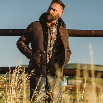 Man wearing the Durango shearling barn coat in Espresso Brown by a ranch fence