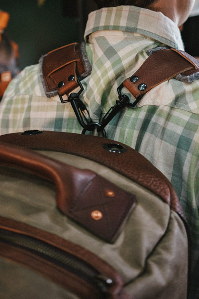 Close-up of a leather-strapped backpack with metal hardware, highlighting craftsmanship and durability.