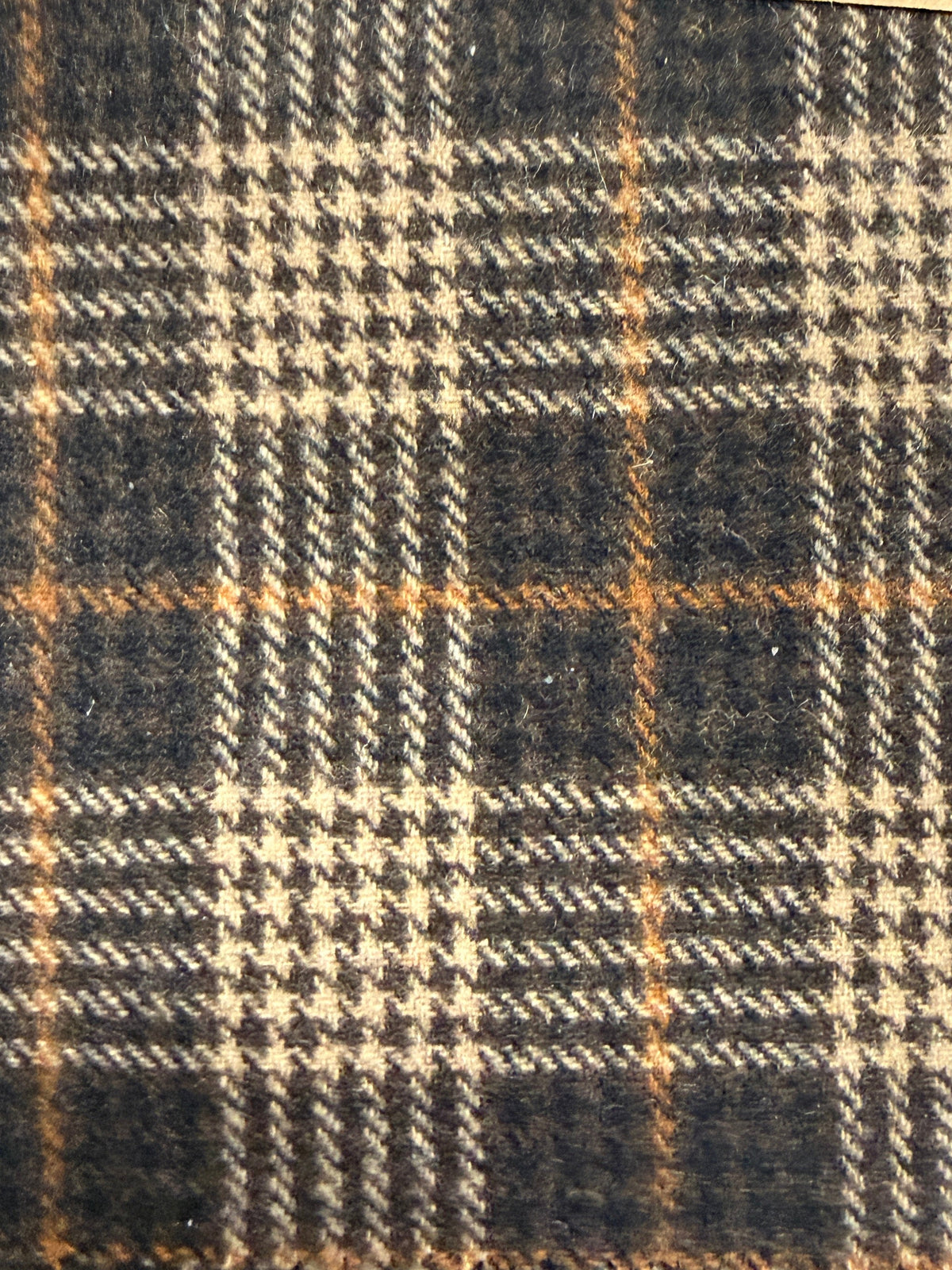 Close-up of a plaid fabric with brown, black, and beige colors.