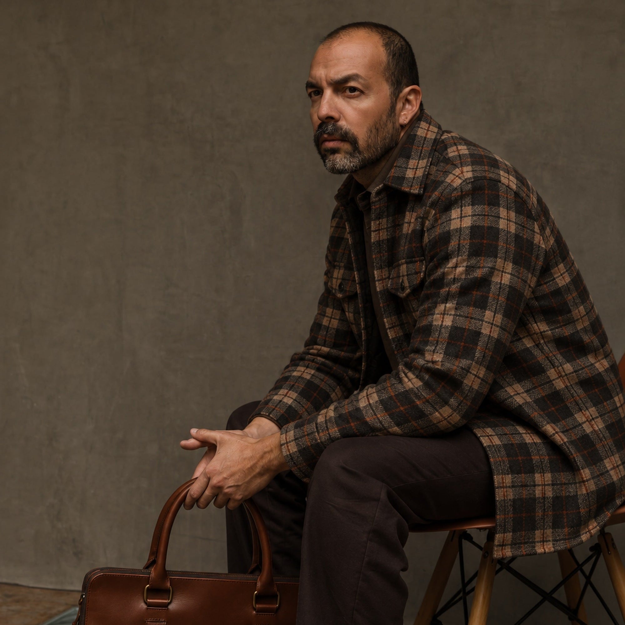 Man in the Aberdeen Wool Twill Shirt Jac in Brown Briar seated on a stool with a leather briefcase