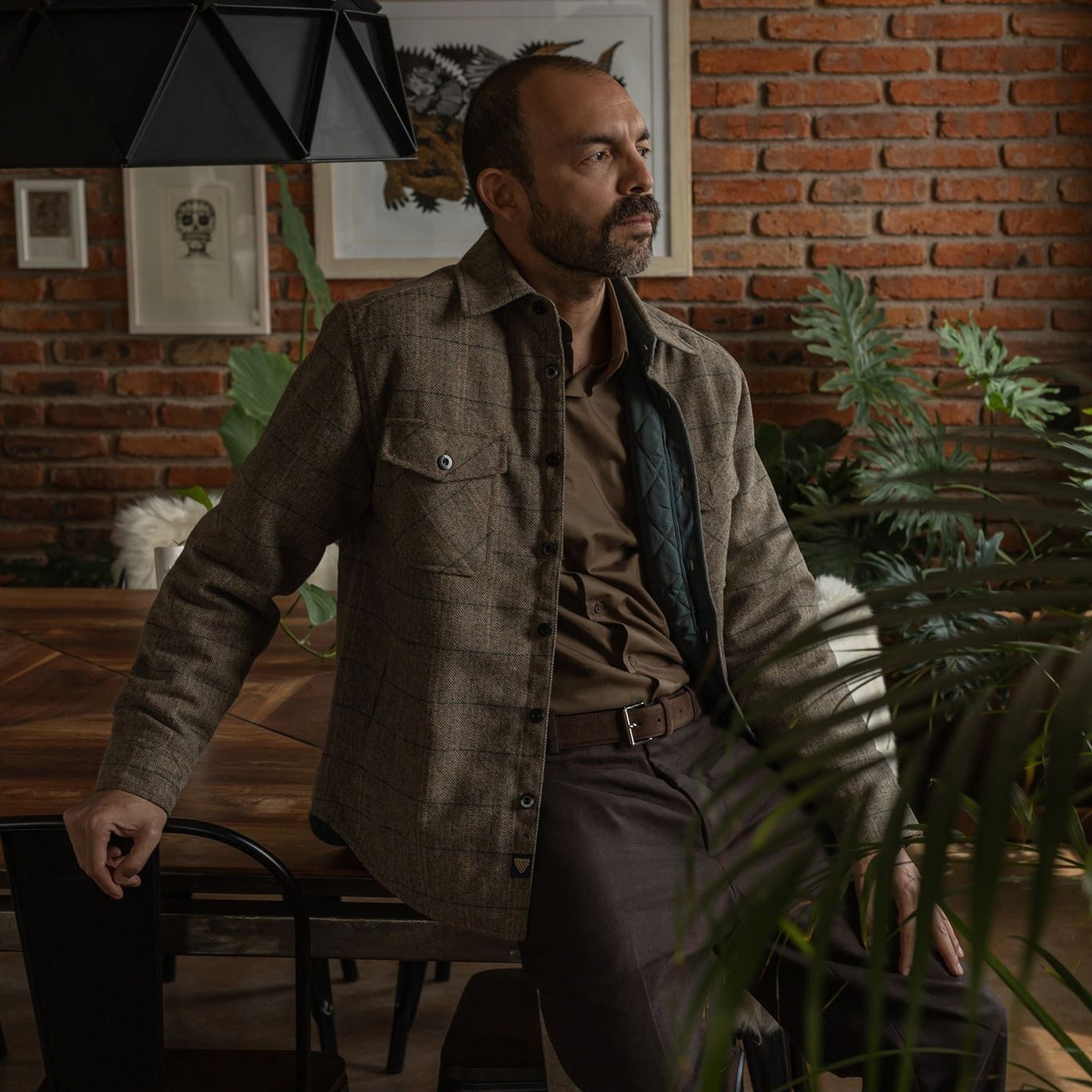 Man in the Aberdeen Wool Twill Shirt Jac in Thistle Grove standing in a brick-walled room