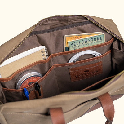 Canvas bag with leather straps and metal fastenings, emphasizing craftsmanship and rugged design.