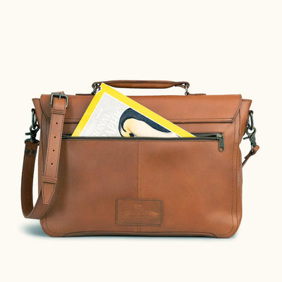 Durable brown leather satchel with subtle embossed logo, offering a classic look with contemporary functionality for the urban commuter, pocket perfect for a magazine.