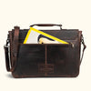 Antique-style dark brown leather satchel with brass hardware, secure turn-lock closure, and a distressed finish for a timeless appeal, pockets perfect to fit a magazine.