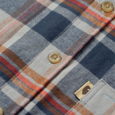Close-up of a plaid fabric with buttons and a brand label.