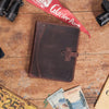 Dark oak Roosevelt leather travel padfolio with secure cross closure and vintage design on a rustic table.