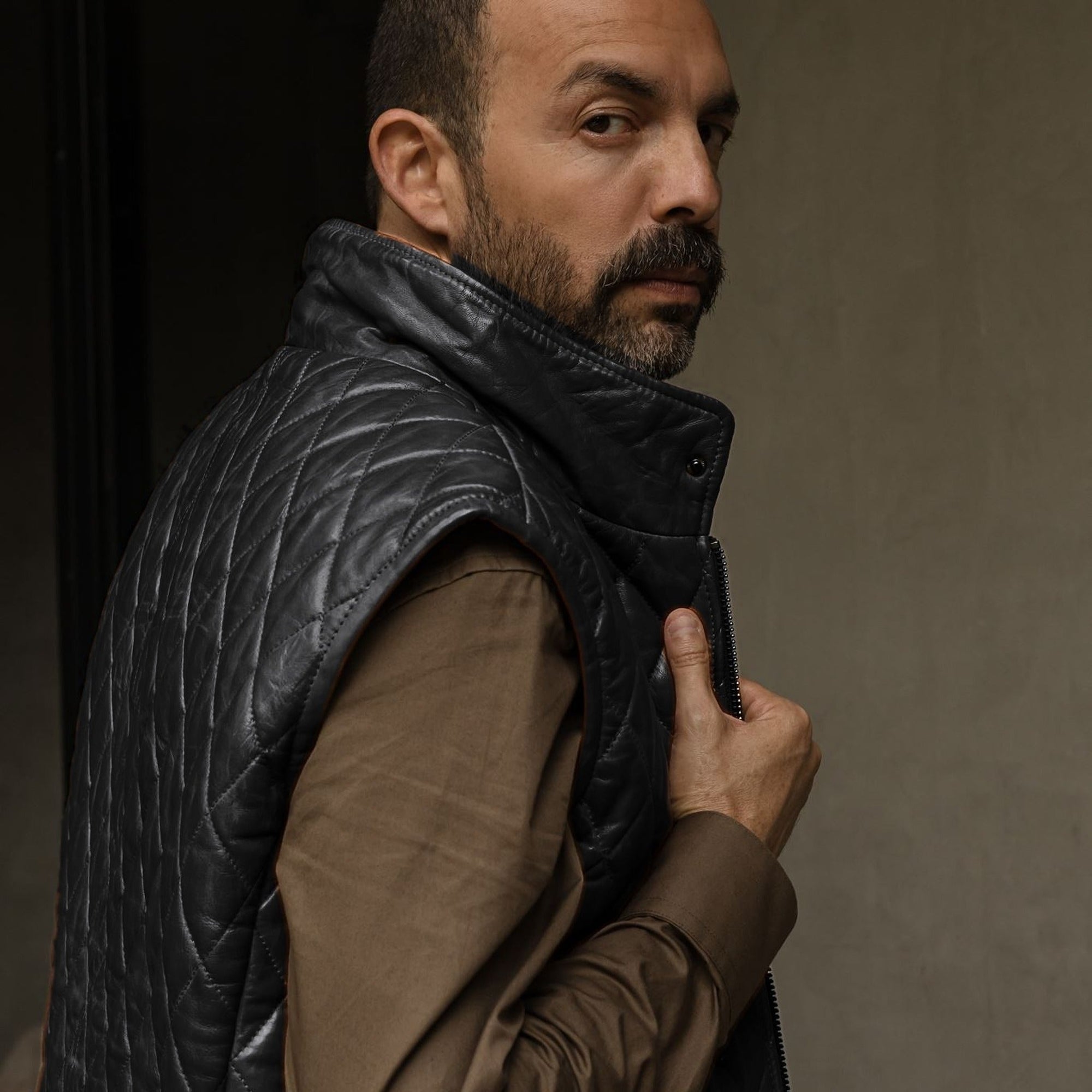 Man in the Highlands Quilted Leather Vest in Black, looking over his shoulder.