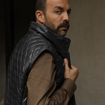Man in the Highlands Quilted Leather Vest in Black, looking over his shoulder.