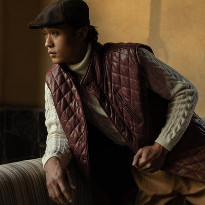 Man in a flat cap leaning forward in the Highlands Quilted Leather Vest in Mahogany Brown.