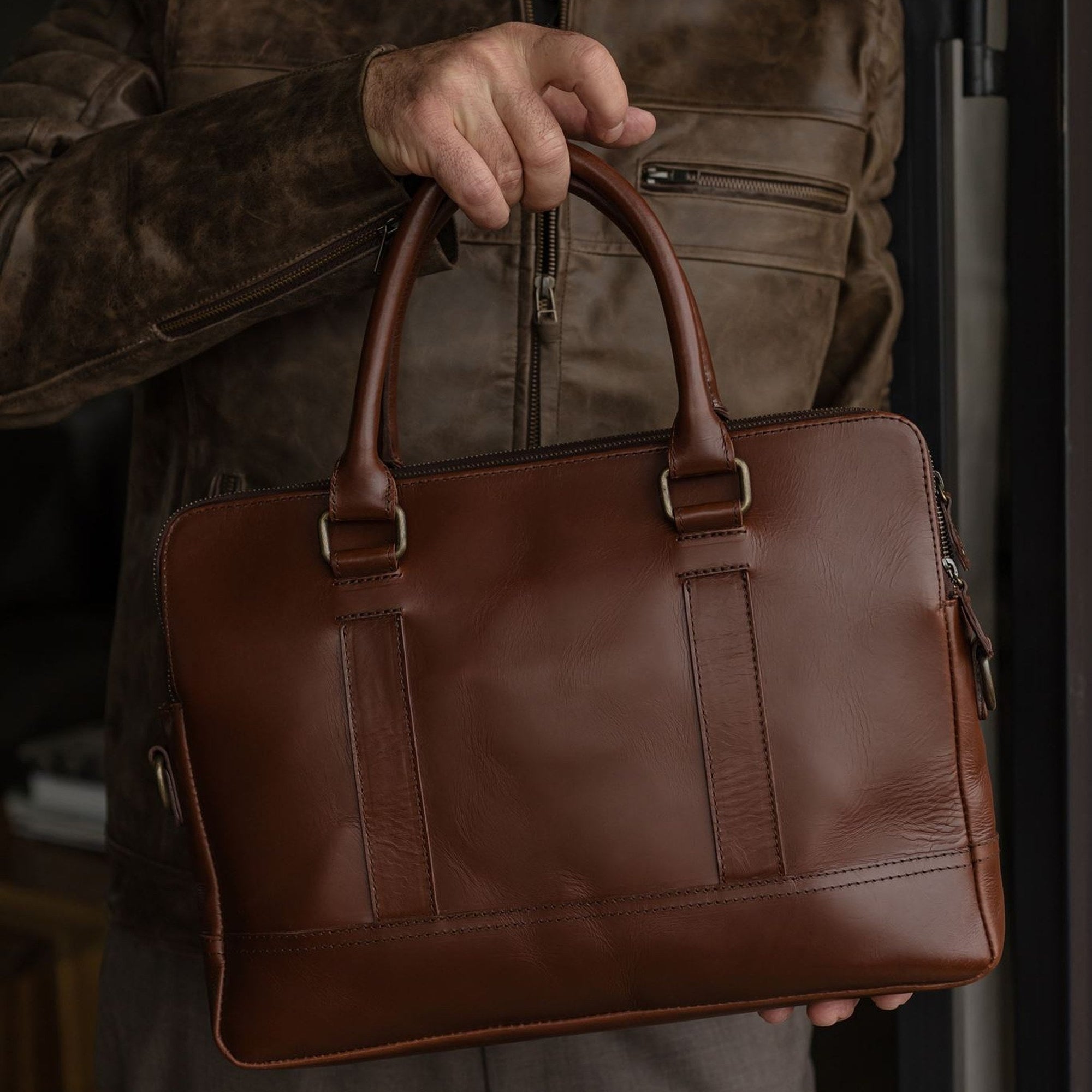 Man holding the Jefferson Leather Attaché Briefcase in Elderwood Brown by its top handles.