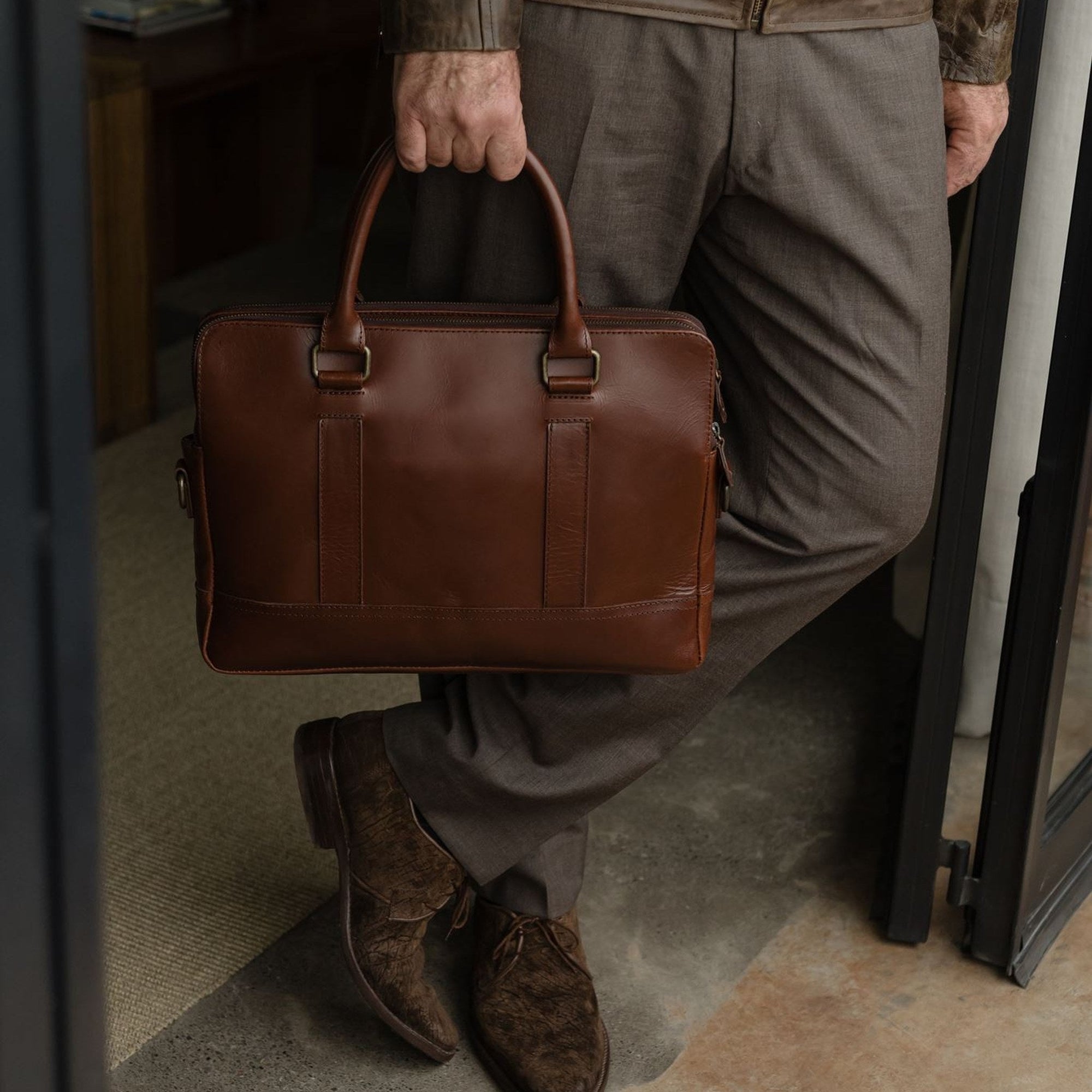 Man standing with the Jefferson Leather Attaché in Elderwood Brown held at his side.