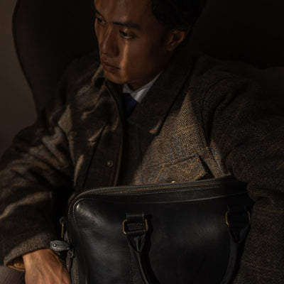 Man seated with the Jefferson Leather Briefcase in Vintage Black on his lap.