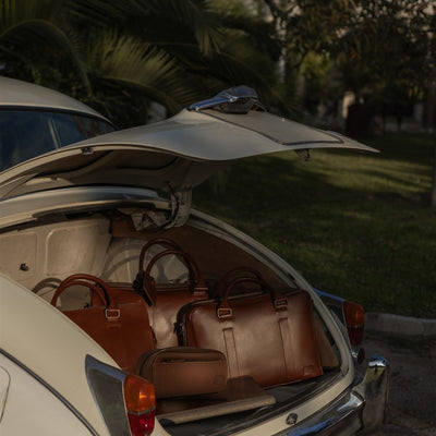 The Jefferson collection in Elderwood Brown, with the Dopp Kit in front, packed in a vintage car trunk.