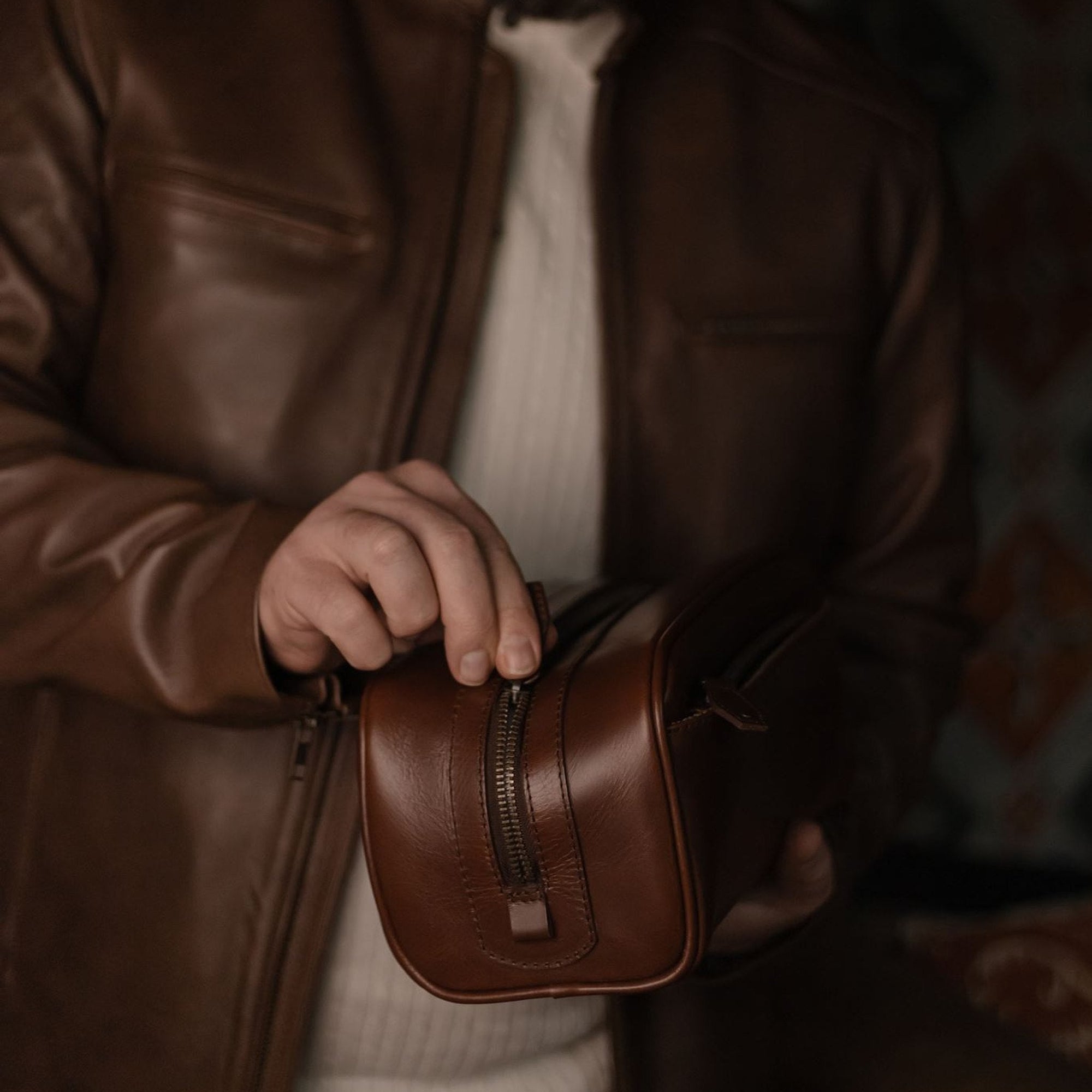 Man unzipping the Jefferson Leather Dopp Kit in Elderwood Brown.