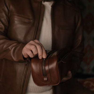 Man unzipping the Jefferson Leather Dopp Kit in Elderwood Brown.