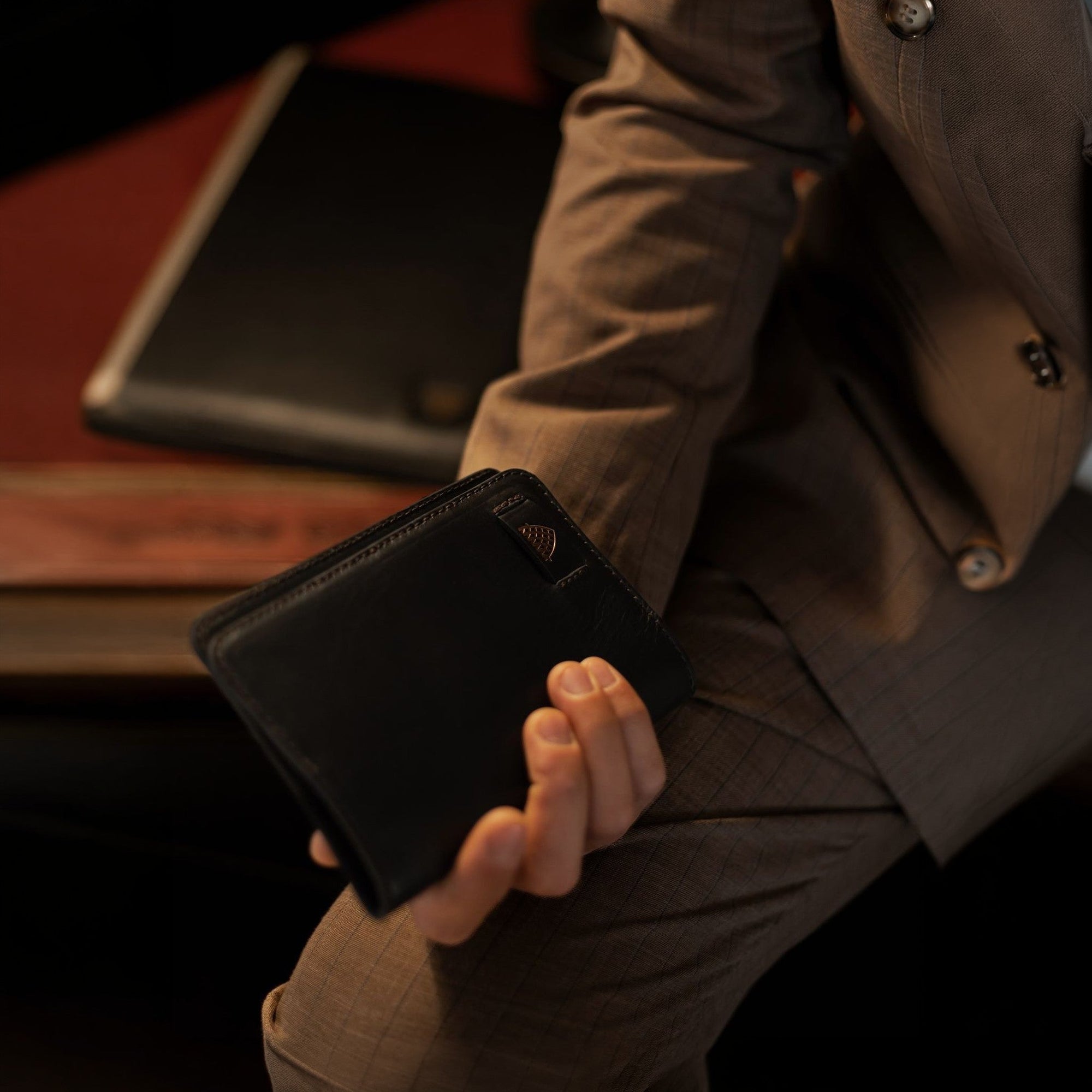 The Jefferson Leather Passport Wallet in Vintage Black held in one hand.