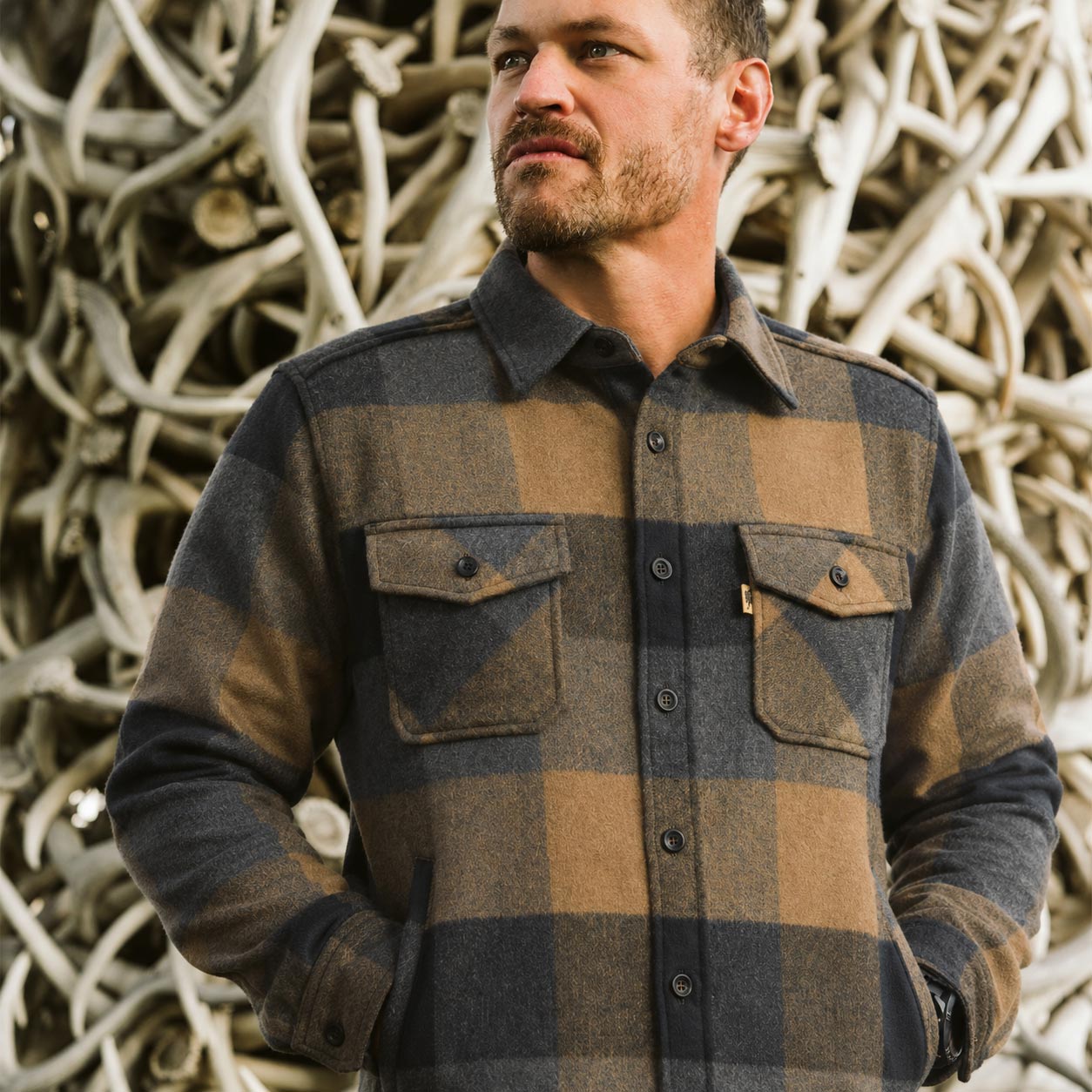 Man wearing a plaid shirt standing in front of Jackson Hole shed sculpture