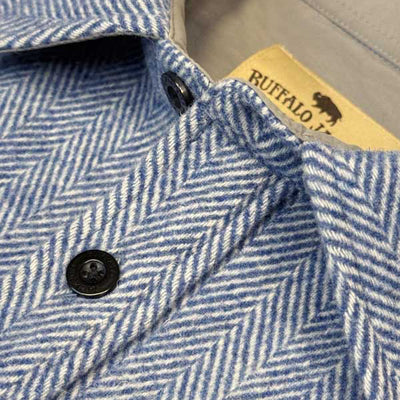 Close-up of a blue and white herringbone patterned shirt jacket with black buttons and a visible Buffalo Jacket brand label inside the collar.