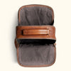 Top view of an open brown leather backpack showing a spacious gray interior with multiple compartments and a zipper closure.