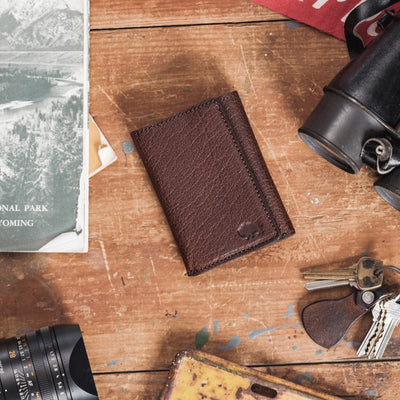 Elegant dark brown bison leather wallet with a trifold design and subtle embossed logo.