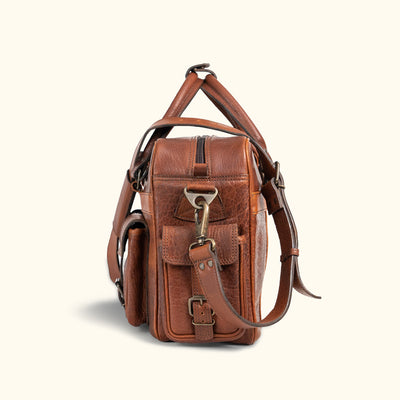 Side View - Rugged full-grain leather satchel with buckle closures and ample storage options;  perfect for professional or casual outings.