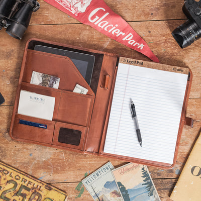 Dark oak leather travel padfolio open to show compartments for a tablet, notepad, cards, and a pen for efficient storage.