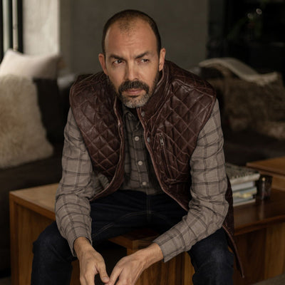 Seated man in the Windsor Cotton Shirt in Timber Pane under a quilted leather vest