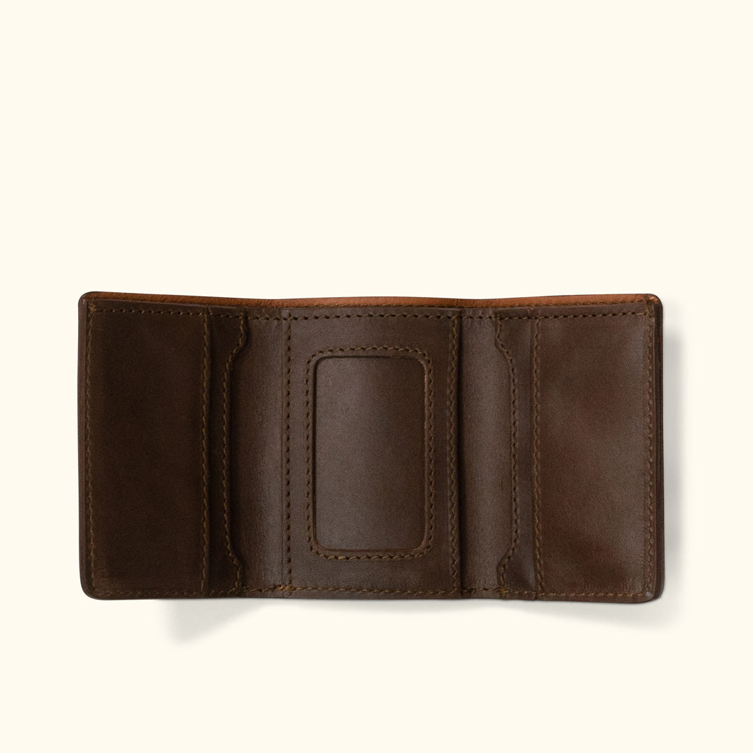 Open brown leather trifold wallet with multiple card slots and a clear ID window.