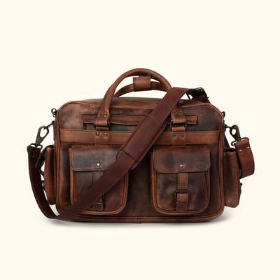 Men's rugged leather pilot bag in dark oak with multiple compartments, brass buckles, adjustable strap, and detachable pouches. Ideal for travel.
