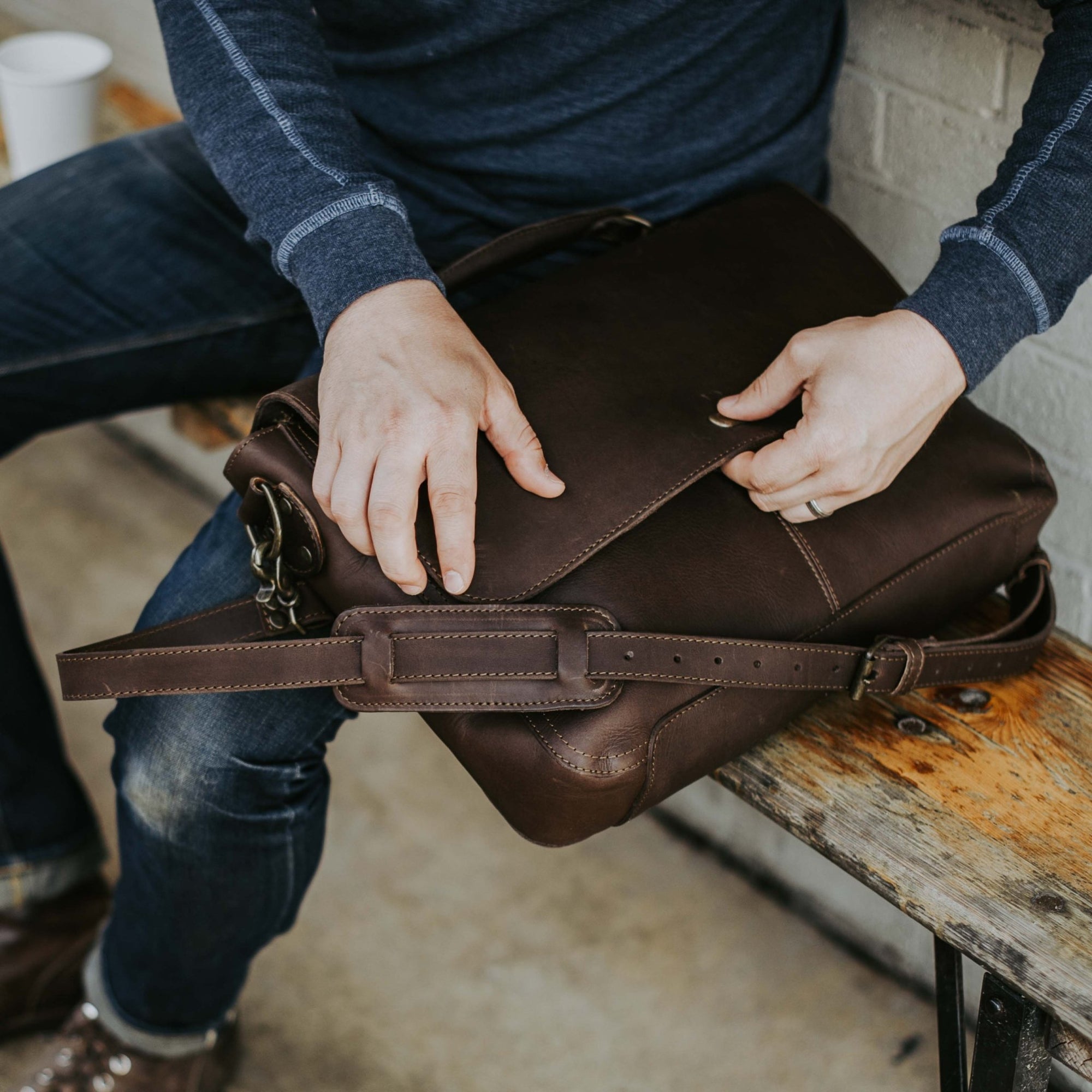 Man at outdoor table with Roosevelt Leather Messenger Bag — Dark Oak full-grain leather, adjustable strap detail