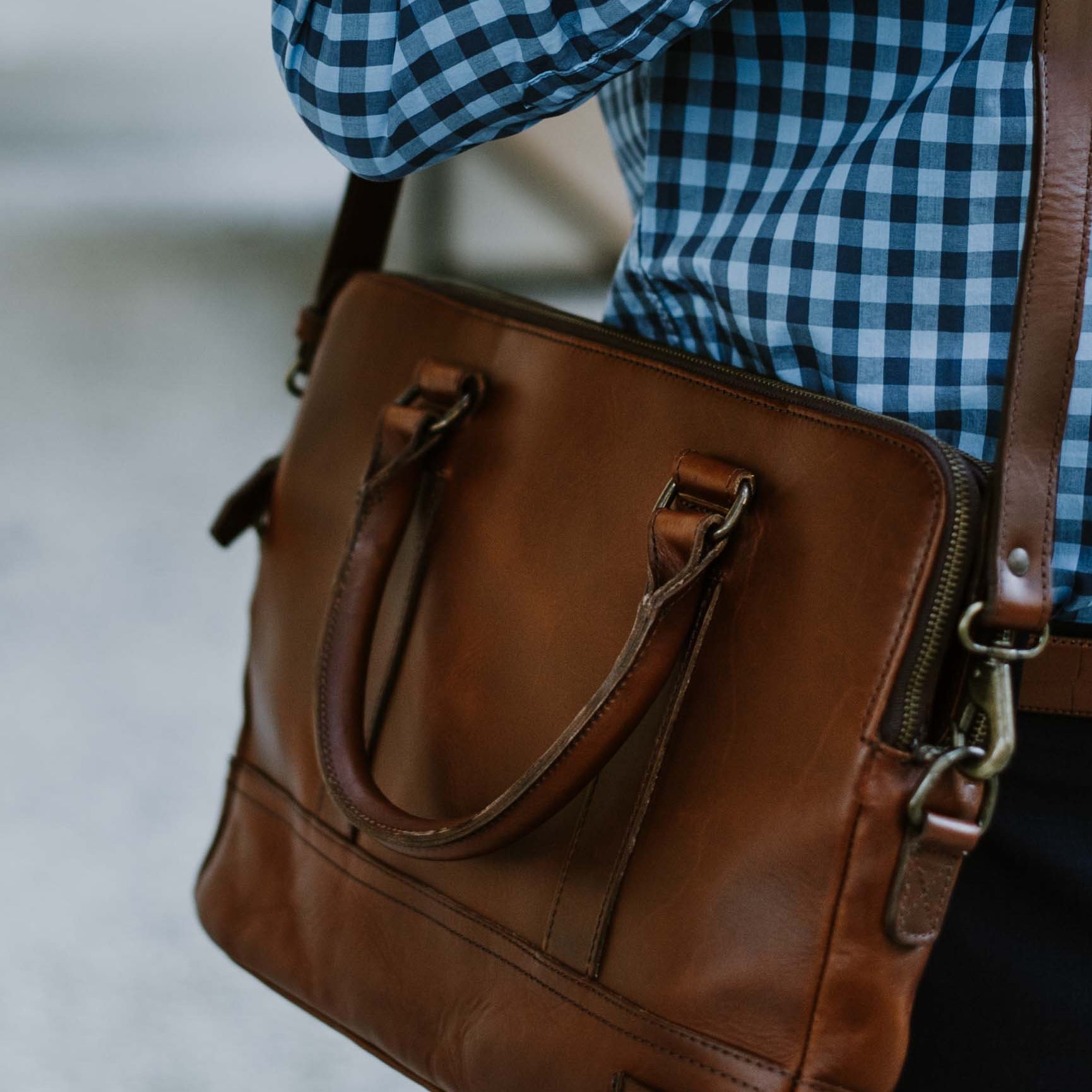 Man in blue checked shirt using a refined leather briefcase.
