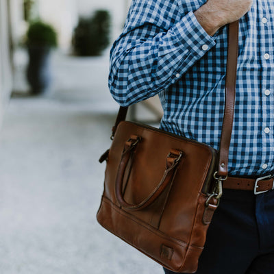 Man in blue checked shirt using a refined leather briefcase.