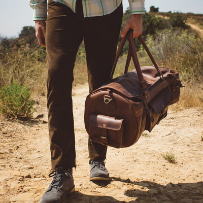 Outdoor adventure with a vintage leather duffle bag, equipped with multiple compartments and a durable shoulder strap.