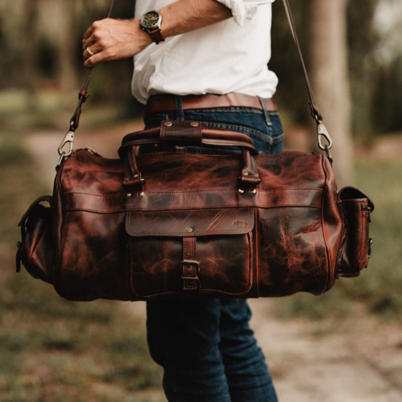 Buffalo leather duffle bag featuring multiple compartments, adjustable shoulder strap, and sturdy handles for travel and daily use.