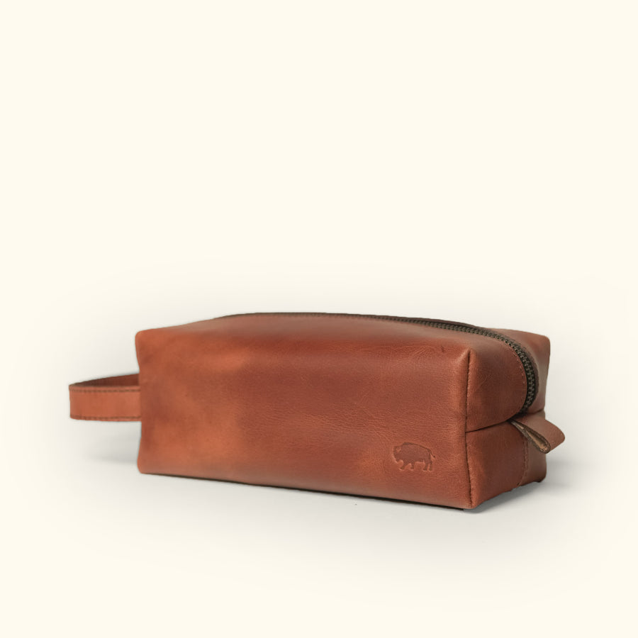Amber brown Roosevelt buffalo leather dopp kit with wrist strap and embossed logo detail.
