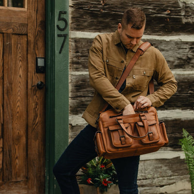Man carrying an amber brown Roosevelt buffalo leather pilot bag, showcasing its versatile design and multiple compartments.