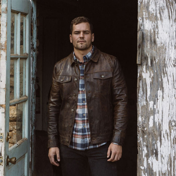 Man wearing a brown leather jacket over a flannel shirt