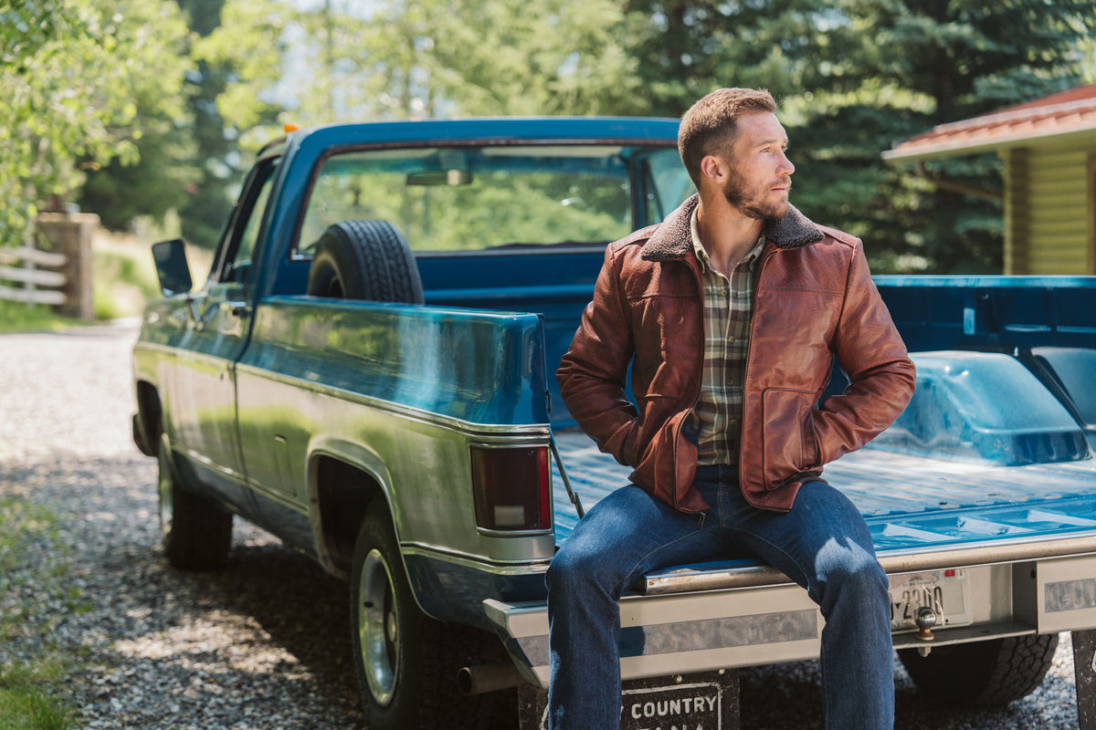 Man wearing Maverick Buffalo Grain Brown leather bomber jacket in outdoor lifestyle setting, showing classic aviator bomber silhouette.