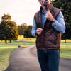 Quilted leather vest in rich mahogany brown, featuring a zippered chest pocket and high neck.
