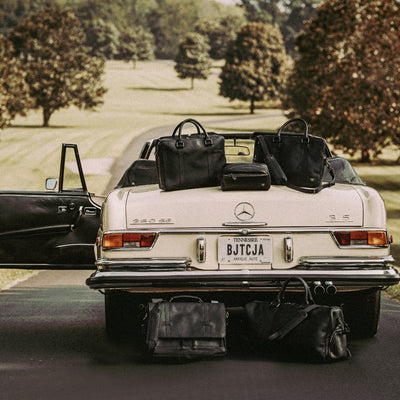 Luxurious black leather bags displayed with a vintage car, highlighting both style and elegance.