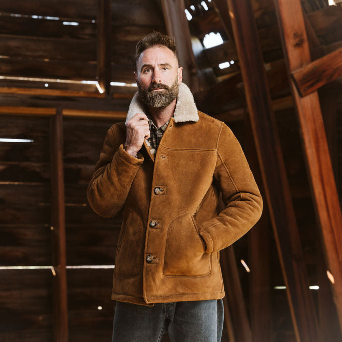Man wearing the Durango shearling barn coat in Saddle Tan in a wooden barn